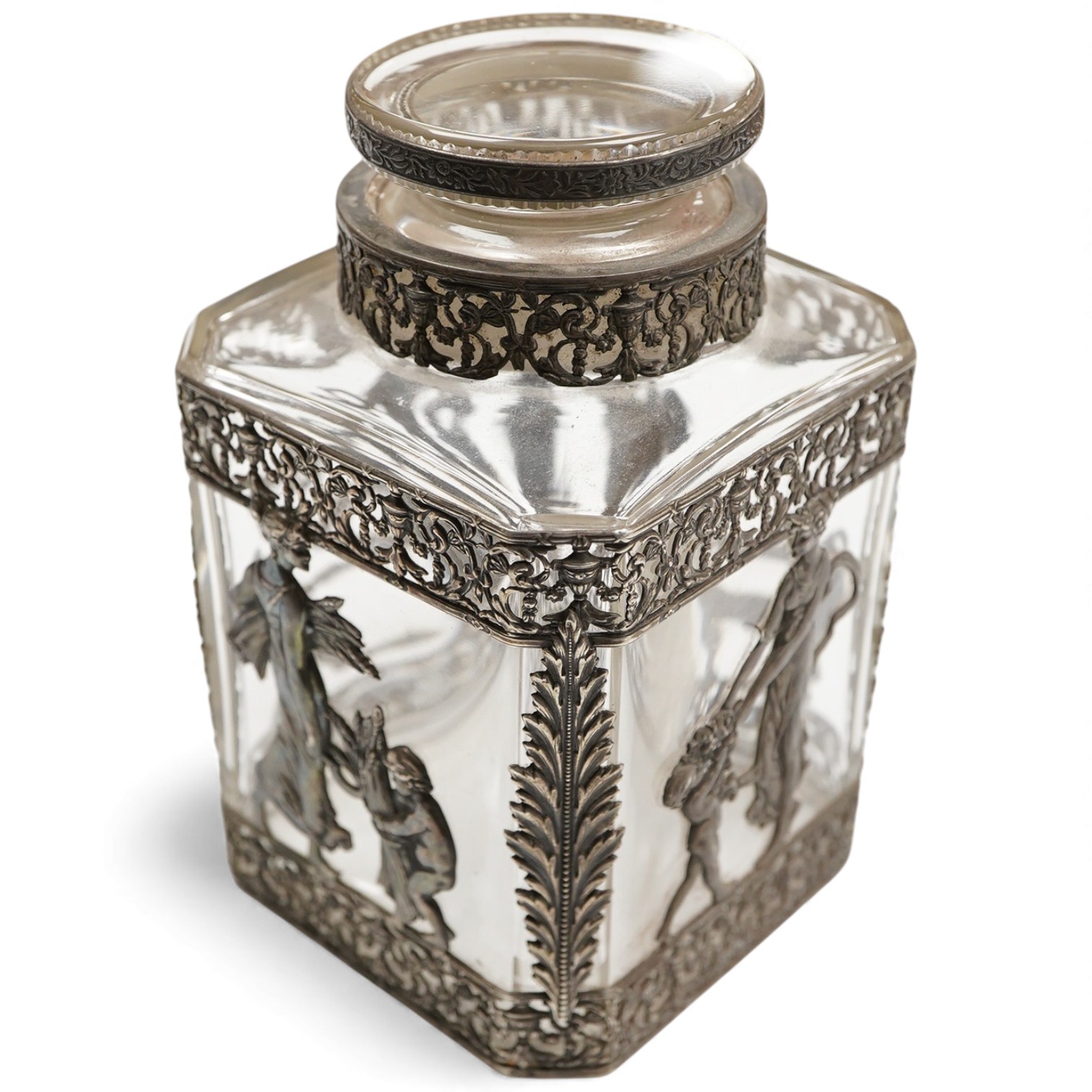 A late 19th/early 20th century French 800 standard pierced white metal mounted glass jar or tea caddy and stopper, decorated with classical scene of a lady with child, height 13.2cm.